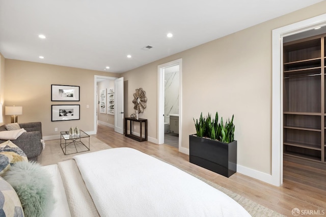 bedroom featuring light hardwood / wood-style floors, a spacious closet, a closet, and ensuite bath