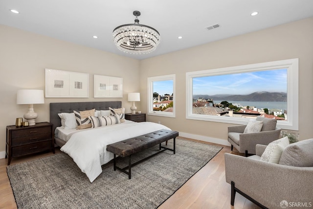 bedroom with light hardwood / wood-style floors, an inviting chandelier, and a mountain view