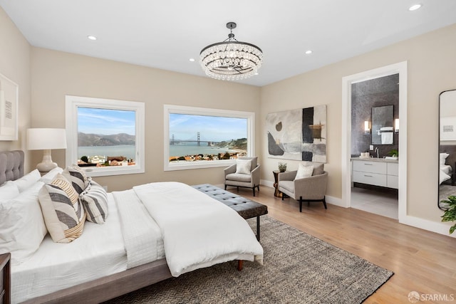 bedroom featuring ensuite bathroom, a chandelier, light hardwood / wood-style floors, and sink