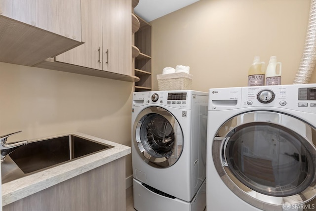 washroom with sink, washer and dryer, and cabinets