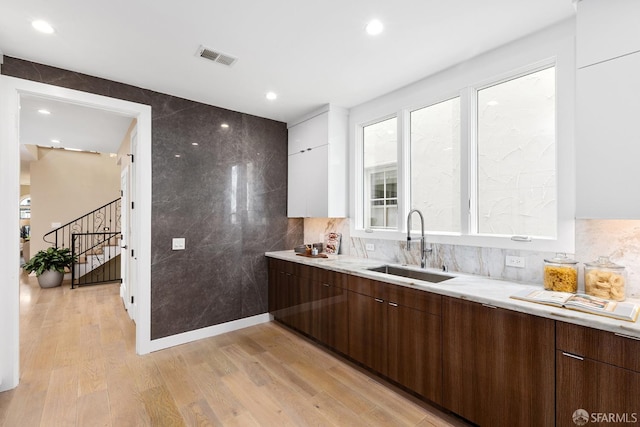 kitchen featuring white cabinetry, dark brown cabinets, light hardwood / wood-style flooring, and sink