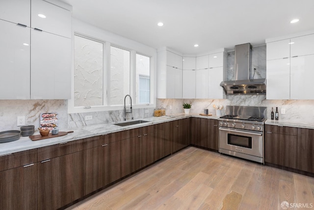 kitchen featuring light hardwood / wood-style flooring, white cabinets, high end stainless steel range oven, and wall chimney range hood