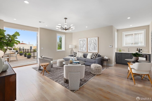 living room featuring an inviting chandelier, light wood-type flooring, and sink