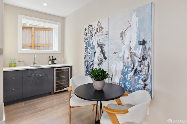 dining area featuring light wood-type flooring, wine cooler, and wet bar