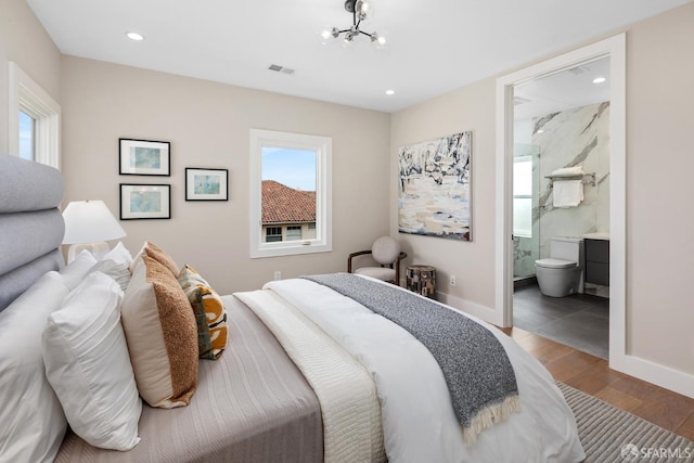 bedroom with an inviting chandelier, hardwood / wood-style floors, and ensuite bath