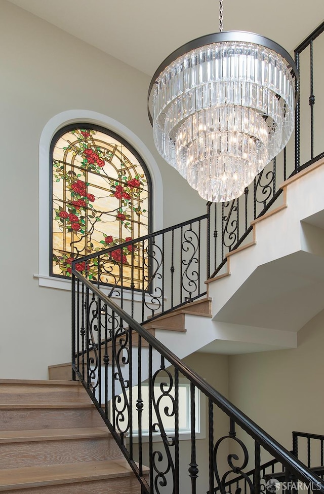 stairway featuring a notable chandelier and a towering ceiling