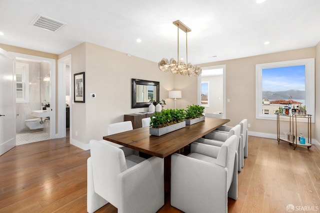 dining space with an inviting chandelier and light hardwood / wood-style flooring