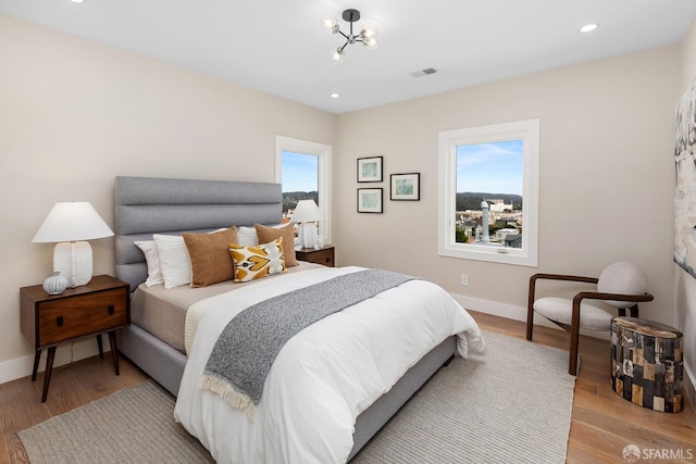 bedroom featuring light hardwood / wood-style flooring and a chandelier