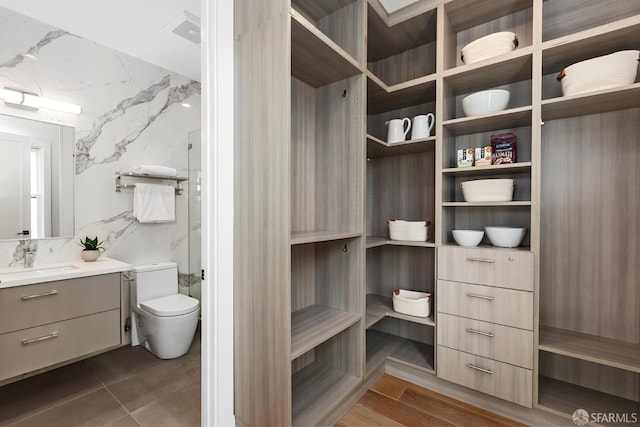 bathroom featuring tile walls, vanity, walk in shower, toilet, and hardwood / wood-style floors