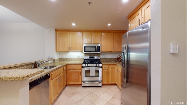 kitchen with light stone counters, stainless steel appliances, sink, and kitchen peninsula