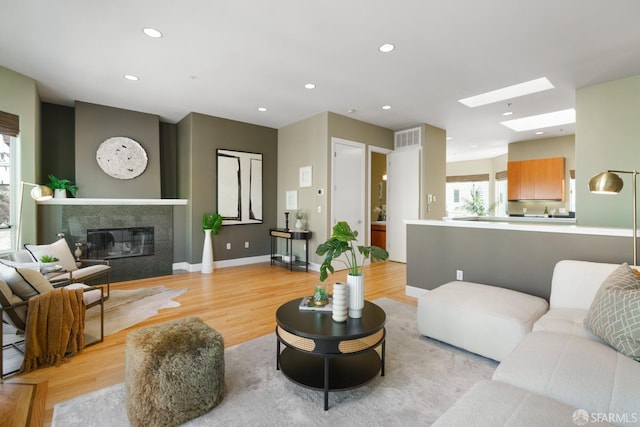 3310 19th St Unit 303, San Francisco, CA 94110 - living room with a skylight, light wood finished floors, recessed lighting, a glass covered fireplace, and baseboards