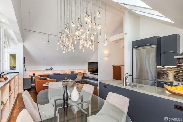 dining space featuring sink, dark wood-type flooring, high vaulted ceiling, and a skylight