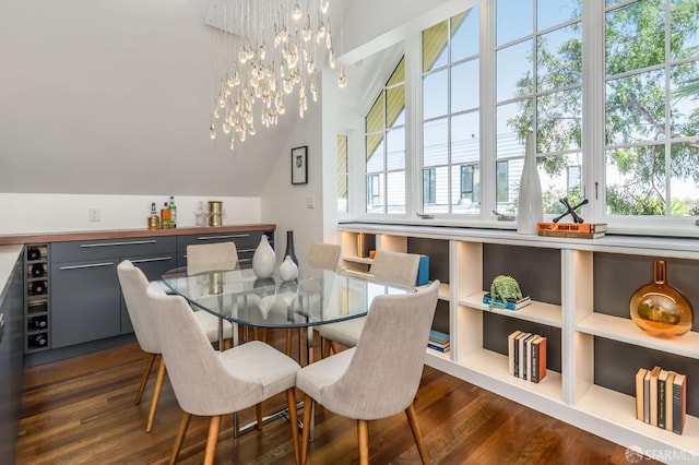 dining area with lofted ceiling, dark hardwood / wood-style floors, and a chandelier