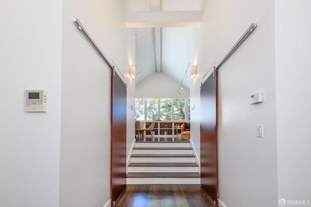 staircase featuring hardwood / wood-style floors and lofted ceiling with beams