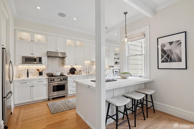 2531 Gough St, San Francisco, CA 94123 - kitchen with stainless steel appliances, under cabinet range hood, a breakfast bar, backsplash, and white cabinetry