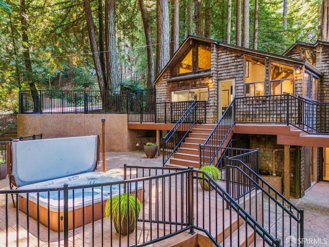 exterior space with a covered hot tub, a deck, and a patio