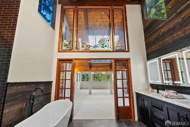 bathroom featuring a tub to relax in, a high ceiling, vanity, and plenty of natural light