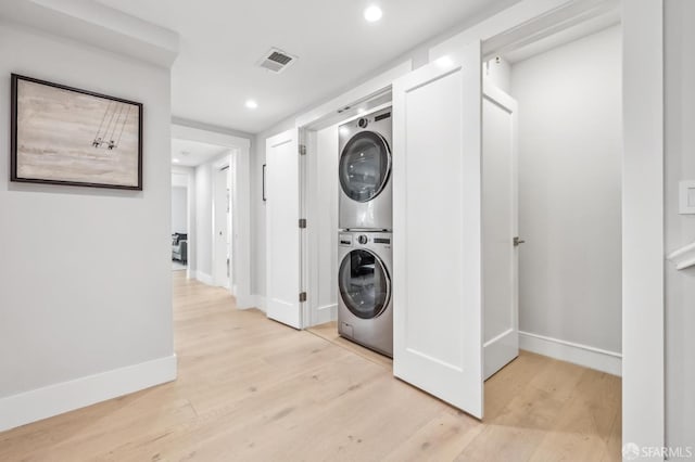 washroom with baseboards, light wood-style floors, laundry area, and stacked washer / dryer