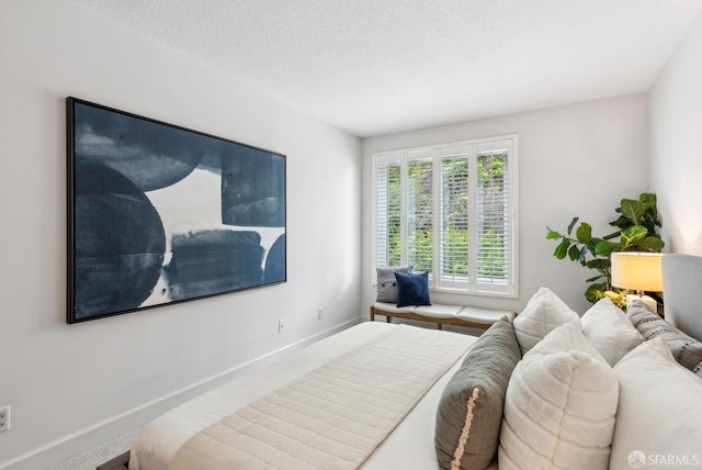 carpeted bedroom featuring baseboards and a textured ceiling