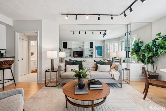 living area with rail lighting, baseboards, and light wood-style floors