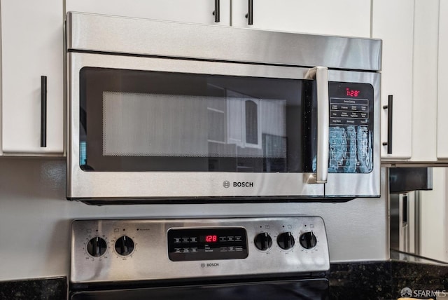 details featuring stainless steel microwave, white cabinetry, and range