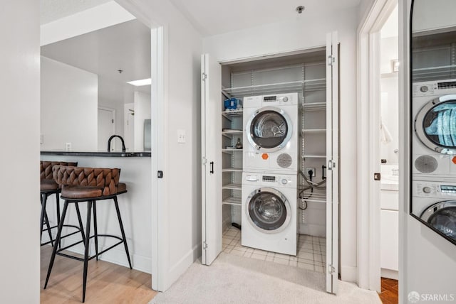 washroom featuring baseboards, stacked washer and clothes dryer, and laundry area