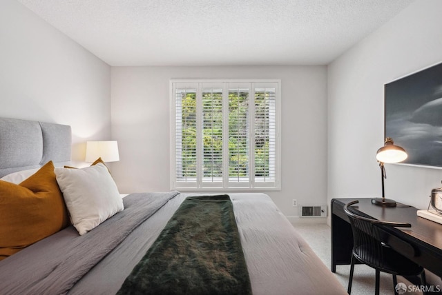 carpeted bedroom featuring a textured ceiling and visible vents