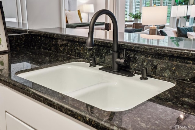 details featuring a sink, dark stone counters, and white cabinets