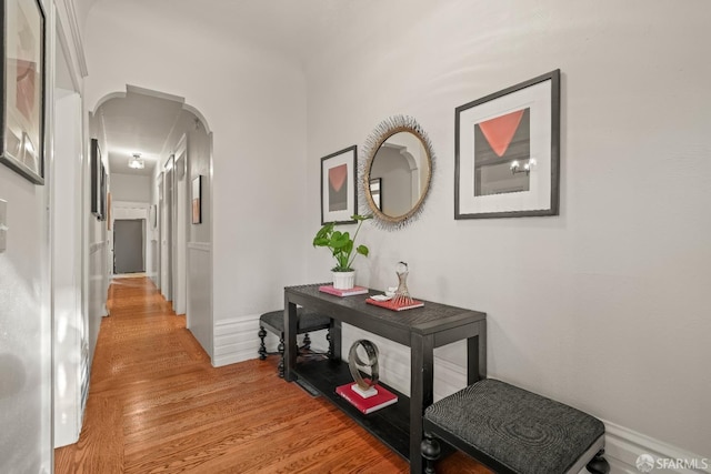 corridor featuring arched walkways and light wood-style floors