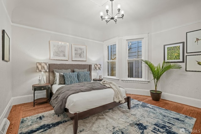 bedroom featuring a chandelier, visible vents, baseboards, and wood finished floors