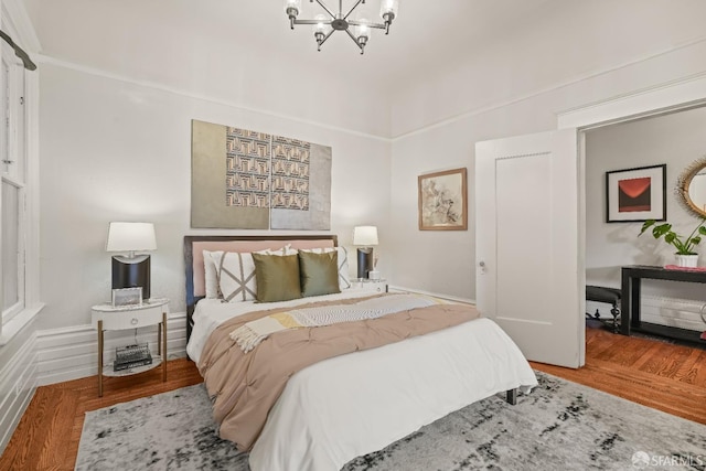 bedroom with wood finished floors and an inviting chandelier