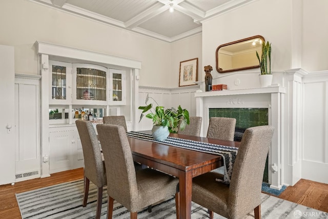 dining room with a wainscoted wall, beamed ceiling, coffered ceiling, and wood finished floors