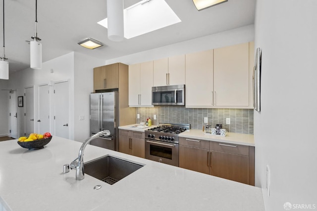 kitchen with appliances with stainless steel finishes, sink, decorative light fixtures, a skylight, and decorative backsplash