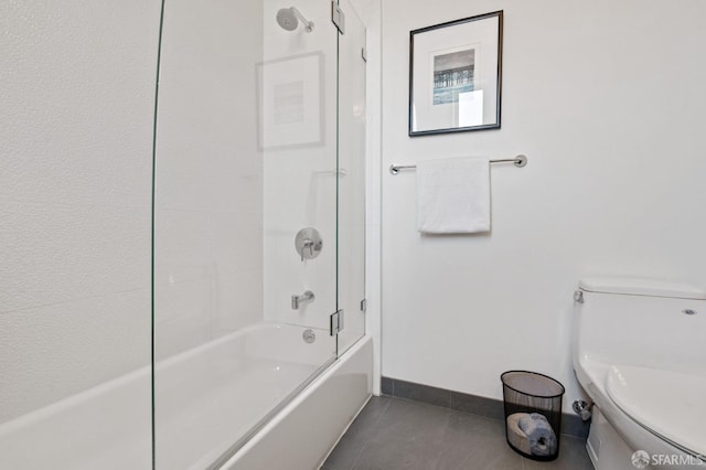 bathroom featuring tile patterned flooring, toilet, and bathing tub / shower combination