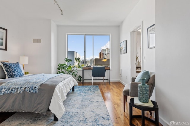 bedroom featuring rail lighting and wood-type flooring