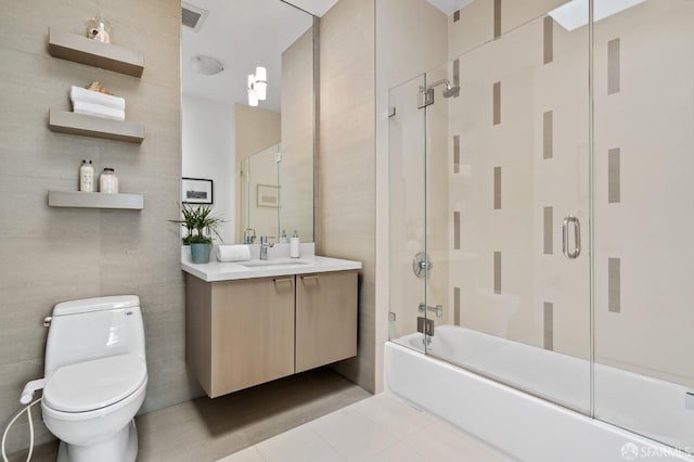 full bathroom with toilet, bath / shower combo with glass door, tile walls, tile patterned flooring, and vanity