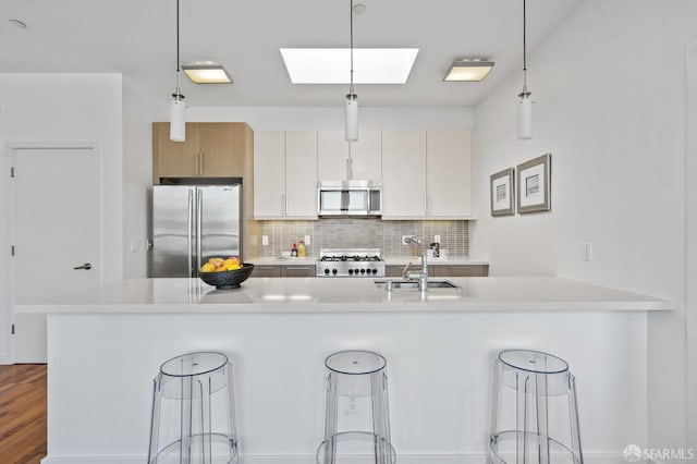 kitchen featuring stainless steel appliances, white cabinetry, a kitchen bar, and decorative light fixtures