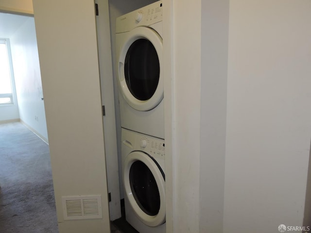 laundry room with stacked washing maching and dryer and carpet flooring