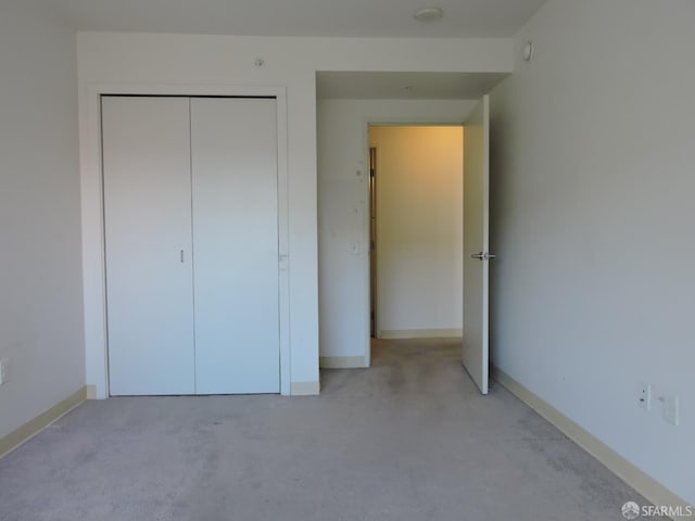 unfurnished bedroom featuring light colored carpet and a closet