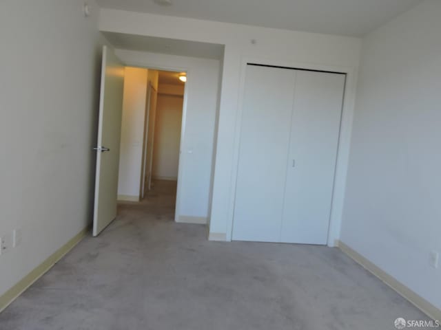 unfurnished bedroom featuring light carpet and a closet