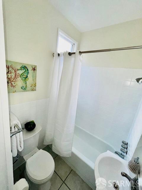 bathroom with shower / tub combo, tile patterned flooring, tile walls, and toilet