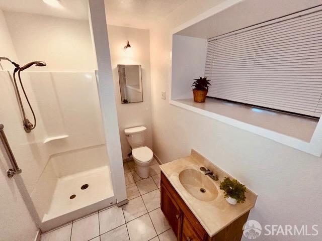 bathroom with vanity, toilet, tile patterned floors, and walk in shower