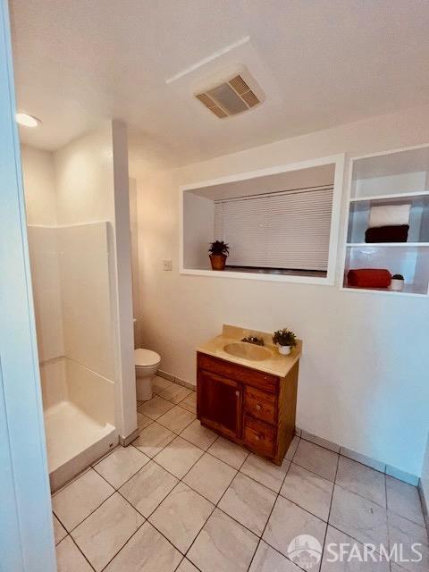 bathroom with tile patterned flooring, a shower, vanity, and toilet