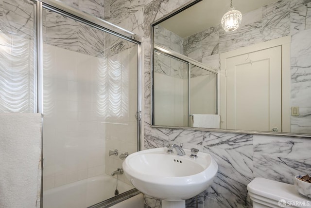 full bathroom featuring combined bath / shower with glass door, a sink, toilet, and tile walls