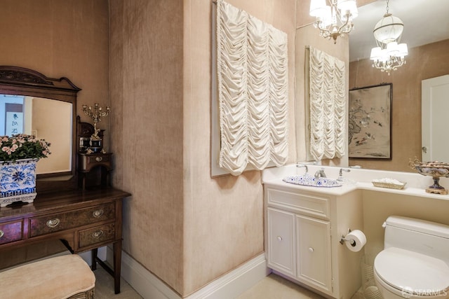 bathroom with toilet, baseboards, a notable chandelier, and vanity