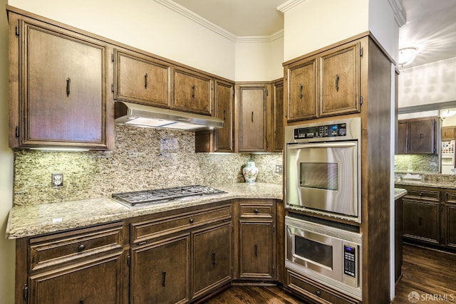 kitchen with ornamental molding, stainless steel gas cooktop, dark wood finished floors, and under cabinet range hood