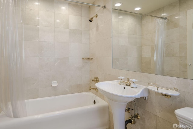 bathroom featuring toilet, shower / bath combo, and tile walls