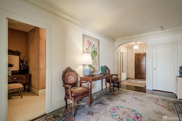 sitting room featuring arched walkways, ornamental molding, and baseboards