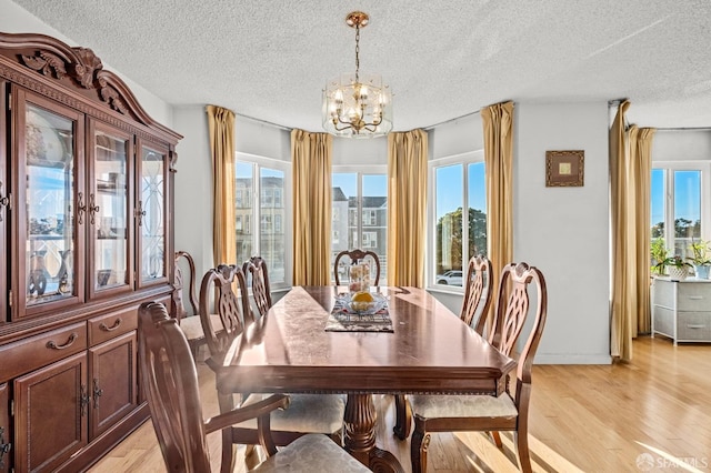 dining room featuring a textured ceiling, an inviting chandelier, baseboards, and light wood-type flooring