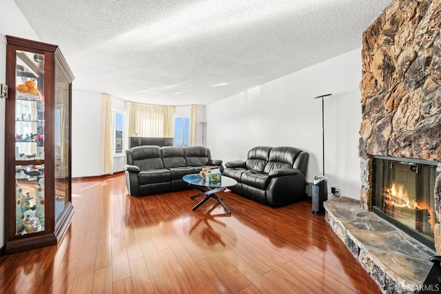 living room featuring a textured ceiling, wood finished floors, and a fireplace